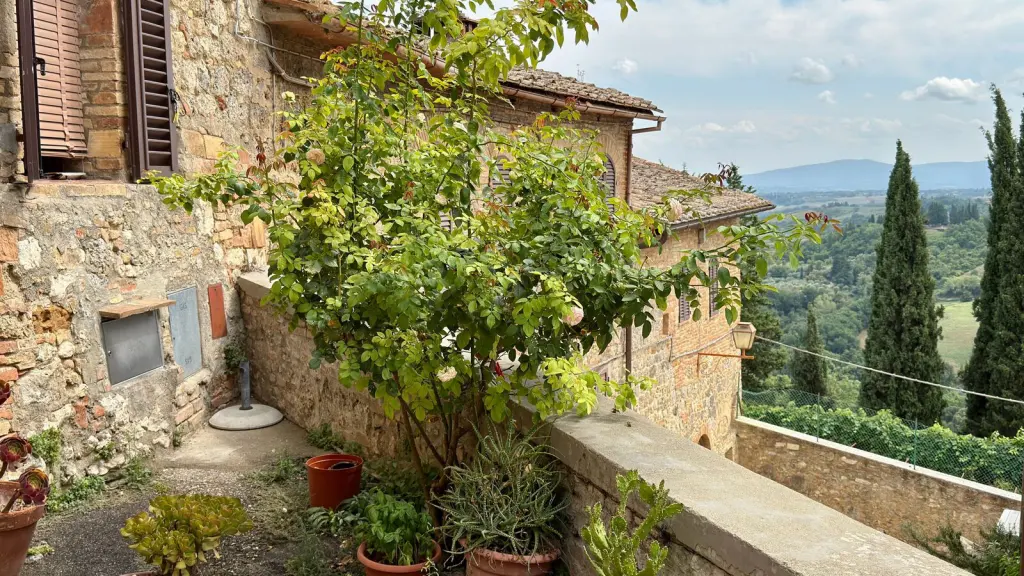 Casa in pietra con le persiane chiuse affacciata su una valle coltivata