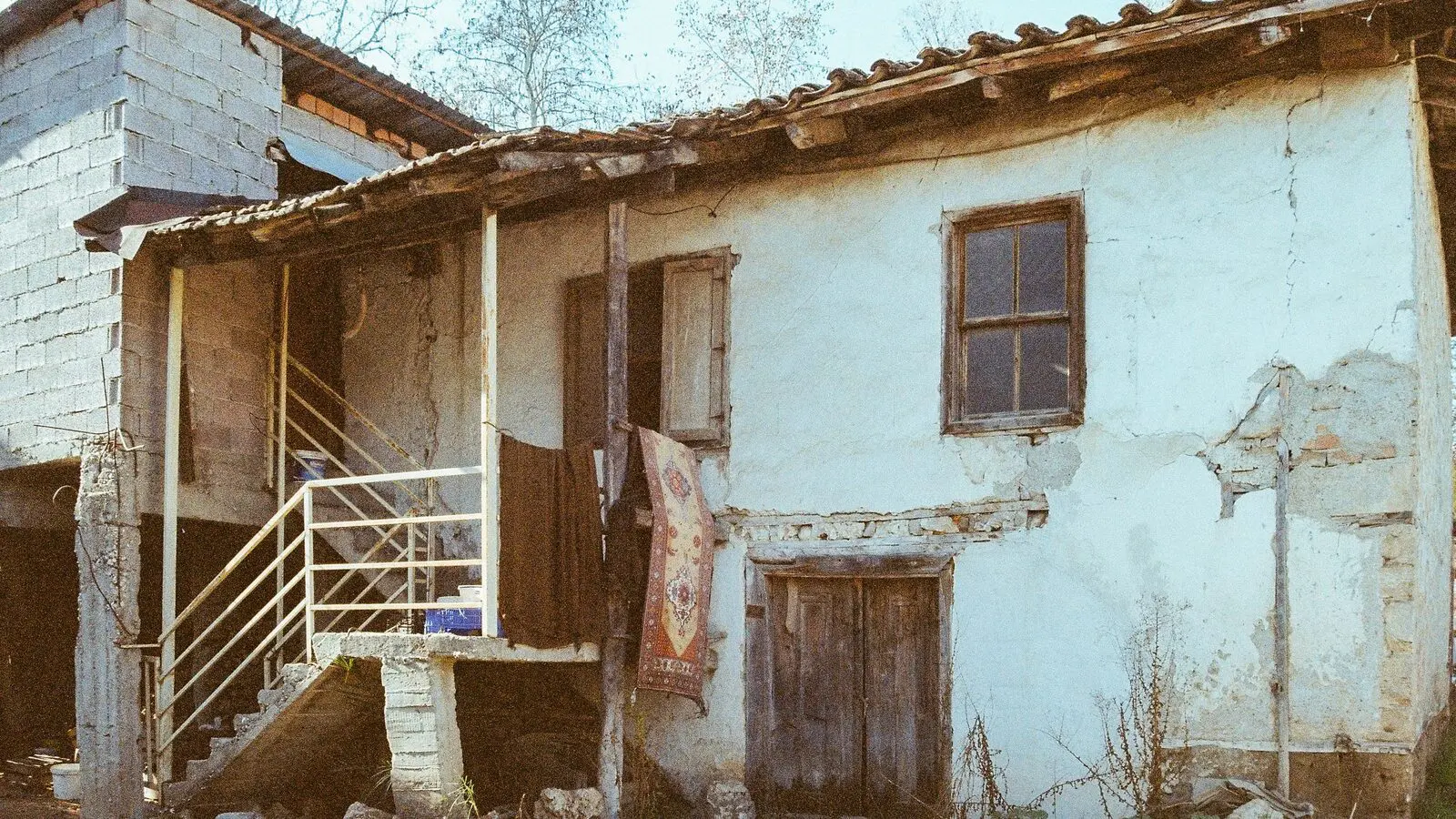 Casa rurale con l'intonaco caduto e una scala esterna in muratura