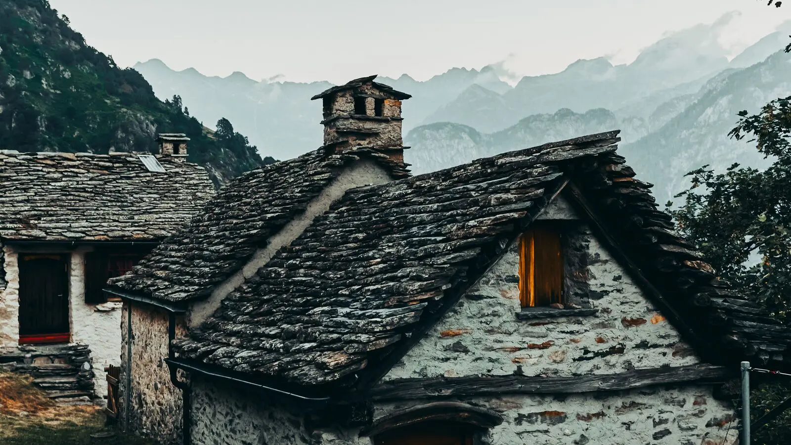 Case in pietra con il tetto in lastre, appoggiate a un pendio di montagna